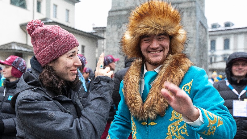 Hannah signs 'r' while he smiles at camera